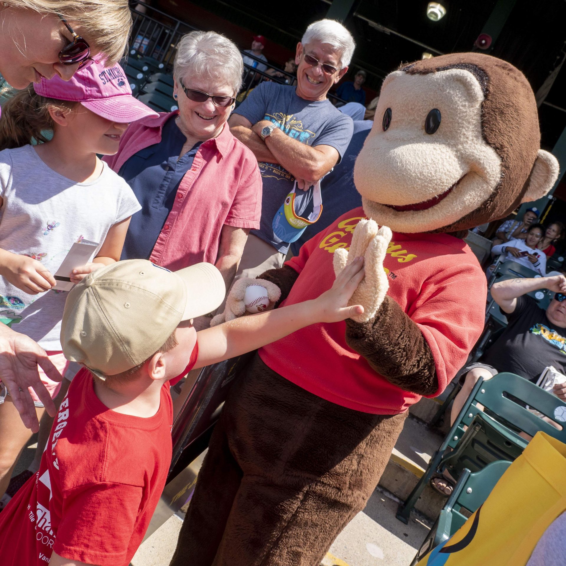 Child giving a high five to Curious George at Back to School Bash event