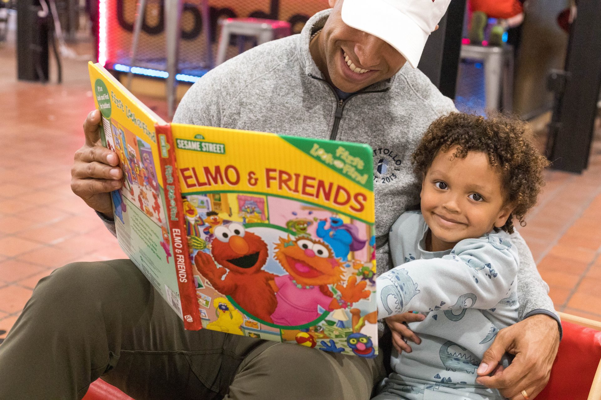 A father reads 'Elmo & Friends' to his child at a WITF Ready Set Explore event.